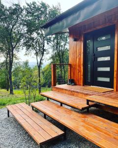 a wooden cabin with two benches in front of it at MoodySun Studio, remote tiny home in Comarnic
