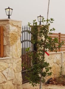 a tree next to a stone fence with a black gate at Villa Reefna in ‘Isfiyā