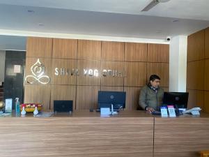 a man sitting at a desk with two laptops at Hotel Shiva Yog Sthal in Rishīkesh