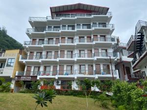 a large white building with balconies and trees at Hotel Shiva Yog Sthal in Rishīkesh