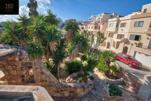- une vue sur un jardin avec des palmiers et une voiture rouge dans l'établissement One of a kind villa with WI-FI, Private pool & BBQ by 360 Estates, à Mellieħa