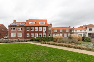 un gran edificio de ladrillo con un césped verde delante de él en Willibrordusplein 28e, en Zoutelande