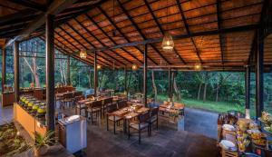 a restaurant with wooden ceilings and tables and chairs at Klov Resort & Spa in Wayanad