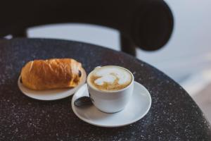 a cup of coffee and a croissant on a table at Kai 36 - Hotel zwischen Fels und Fluss in Graz