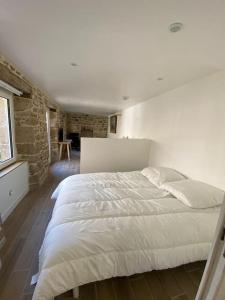 ein weißes Bett in einem Zimmer mit Ziegelwand in der Unterkunft Studio cosy tout équipé en cœur de ville au calme in Guingamp