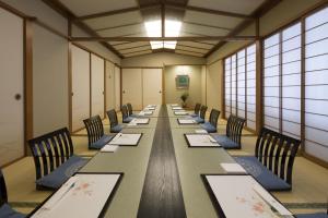 a long table with chairs in a room with windows at Miyako Hotel Yokkaichi in Yokkaichi