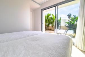 ein Schlafzimmer mit einem weißen Bett und einem großen Fenster in der Unterkunft BEACH NEST VILLA in Son Serra de Marina