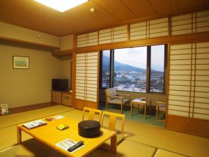 Rainbow Sakurajima في Sakurajima: غرفة معيشة مع طاولة وكراسي ونافذة