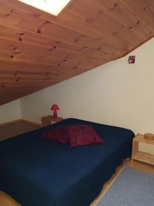 ein Schlafzimmer mit einem blauen Bett und einer Holzdecke in der Unterkunft APPARTEMENT ANCELLE in Ancelle