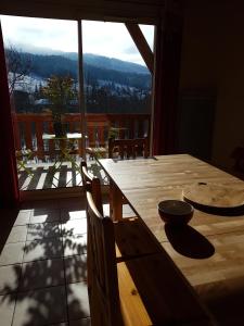 einen Holztisch und Stühle in einem Zimmer mit einem großen Fenster in der Unterkunft APPARTEMENT ANCELLE in Ancelle
