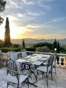 einen Tisch und Stühle auf einer Terrasse mit Blick auf den Sonnenuntergang in der Unterkunft Villa Domaine Font Mourrier in Cogolin