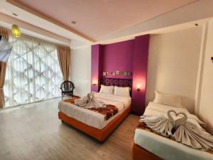 a bedroom with two beds and a purple wall at Langit Langi Hotel @ Port Dickson in Port Dickson