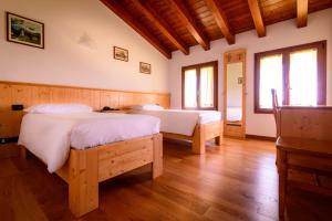 two beds in a room with wooden floors and windows at Agriturismo Nonis in San Vito al Tagliamento