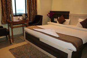 a hotel room with a bed and a desk with a table at Hotel Vaishnavi Heights in Aurangābād