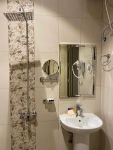 een badkamer met een wastafel en een douche met een spiegel bij القصر المطار in Abha