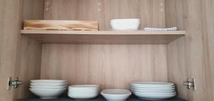 three bowls and plates on a shelf in a kitchen at Charmant logement neuf in Hourtin