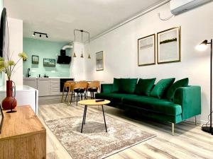 a living room with a green couch and a kitchen at Sunset View Apartment in Timişoara