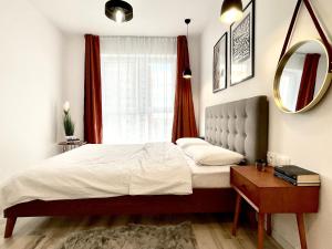 a bedroom with a bed and a mirror and a window at Sunset View Apartment in Timişoara