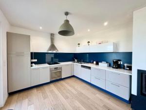 a large kitchen with white cabinets and blue walls at COC - L'Idéal in Hervelinghen