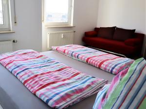 two beds in a room with a red couch at Exklusive Wohnung mit Dachterrasse in Schleußig in Leipzig
