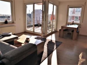 ein Wohnzimmer mit einem Sofa, einem Tisch und Fenstern in der Unterkunft Exklusive Wohnung mit Dachterrasse in Schleußig in Leipzig