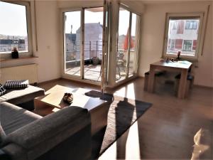a living room with a couch and a table and windows at Exklusive Wohnung mit Dachterrasse in Schleußig in Leipzig