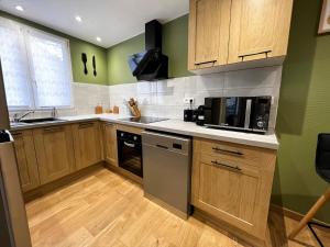 une cuisine avec des murs verts et des armoires en bois dans l'établissement Au Duplex de Jeannala, à Sélestat 25 autres photos