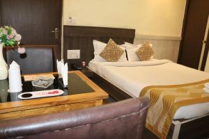 a hotel room with two beds and a table with a chair at Hotel Vaishnavi Heights in Aurangābād