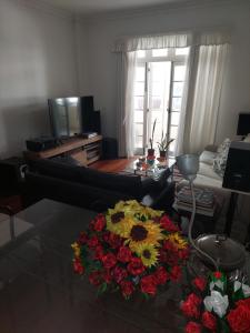 a living room with a table with a bouquet of flowers at Quartos em Laranjeiras in Rio de Janeiro