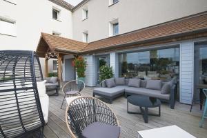 un patio con sofás, mesas y sillas en Les Suites - Konine 4 - Hotel & Bar & Restaurant, en Montceau-les-Mines