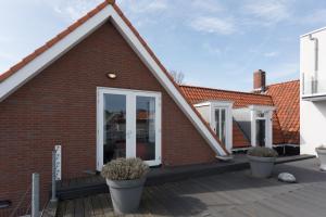 een stenen huis met een veranda met potplanten bij Hello Zeeland - Appartement Markt 5 en 5A in Domburg