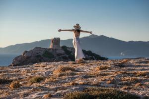 a woman in a white dress standing on top of a hill at Villaggio Camping Torre Del Porticciolo in Porto Conte