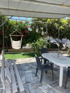 d'une terrasse avec une table blanche, des chaises et un hamac. dans l'établissement Michael&Marika's Traditional House, à Limenaria