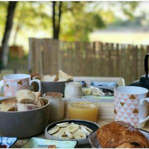 uma mesa com alimentos para o pequeno-almoço e café e sumo de laranja em Chalet avec spa à Libourne proche St-Emilion em Libourne