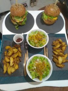 uma mesa com pratos de comida com hambúrgueres e batatas fritas em Chalet avec spa à Libourne proche St-Emilion em Libourne
