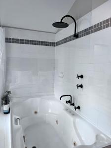 a white bath tub in a white tiled bathroom at MARGARET FOREST RETREAT Apartment 129 - Located within Margaret Forest, in the heart of the town centre of Margaret River, spa apartment! in Margaret River Town +17 photos