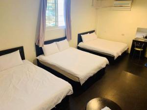 a room with two beds and a table and a window at Jin Lu Homestay in Jincheng