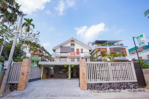 a house with a white fence and palm trees at Lucky Home in Hue