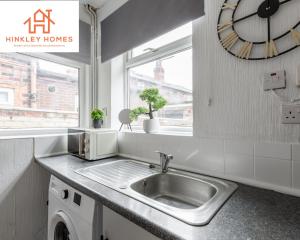 una cucina con lavandino e orologio sul muro di Stanley House - 7 doubles! - Parking! - City Links By Hinkley Homes Short Lets & Serviced Accommodation a Liverpool