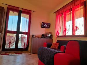 sala de estar con cortinas rojas y sofá en Appartamento Sofia - Nord Sardegna - Badesi, en Badesi