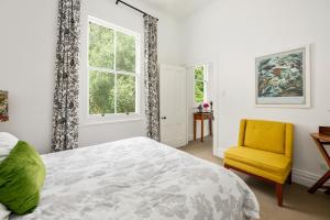 1 dormitorio con 1 cama y 1 silla amarilla en Ports Keep - Napier Holiday Home en Napier