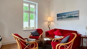 a living room with a red couch and chairs at Villa Sonneck - Wohnung 7 in Ostseebad Sellin