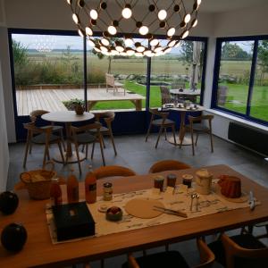 comedor con mesa, sillas y ventanas en Maison HOUX en Dominois