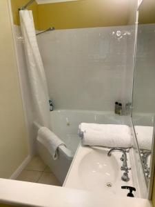 a bathroom with a sink and a tub with towels at Orange Blossom- Comboyne Mountain Cottages in Comboyne