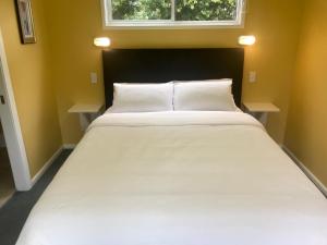 a large white bed in a room with a window at Orange Blossom- Comboyne Mountain Cottages in Comboyne