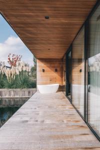 a wooden walkway leading to a bath tub in a house at Haven Lake Village in Kortenhoef