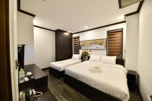 a hotel room with two beds with white sheets at Kingdom Hotel Hanoi in Hanoi