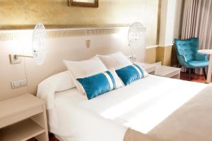 a bedroom with a white bed and a blue chair at Hotel Alfonso VIII in Soria