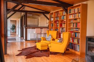 a living room with yellow chairs and bookshelves at Gästehaus auf tollem Anwesen in Neubulach