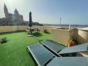 balcón con césped verde, mesa y sillas en Unique Mellieha views, Sea Breeze en Mellieħa